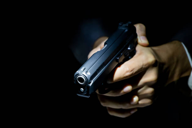 istock male hand holding gun with dark background 1025911330