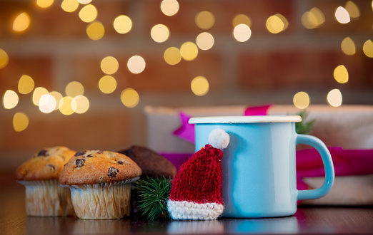 Homemade classic and chocolate cupcakes and cup. Fairy lights in bokeh background. Christmas time concept