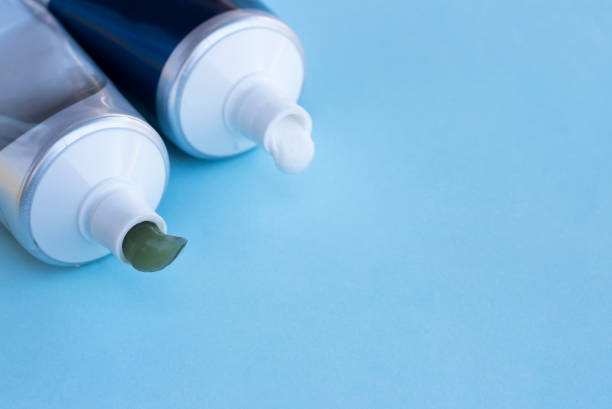 istock Green and white toothpaste squeezed out of tubes on blue background, copy space 1025922840