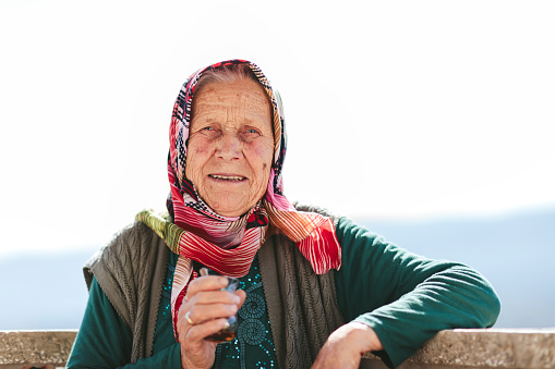 A Turkish senior woman is happily looking at camera and drinking tea.