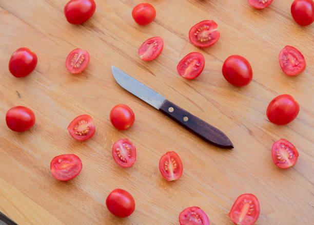 istock Knife and tomatoes on wooden table 1025932804