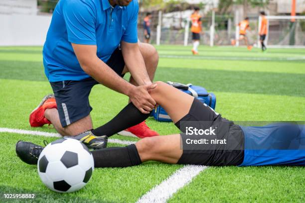 Footballer Wearing A Blue Shirt Black Pants Injured In The Lawn During The Race Stock Photo - Download Image Now