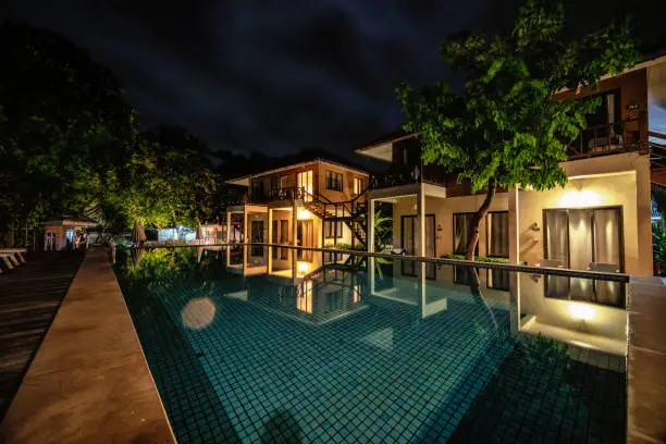 long exposure night shot image of poolside resort building with swimming pool and pool chairs along pool side at Samed Cabana Samed island Rayong Thailand