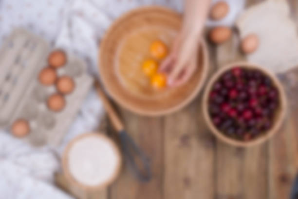 チェリーと自家製の甘いペストリーの準備。卵、小麦粉、木製の背景の果実。女性は、木製の椀に分割卵を手します。コピー スペース - text ready ストックフォトと画像