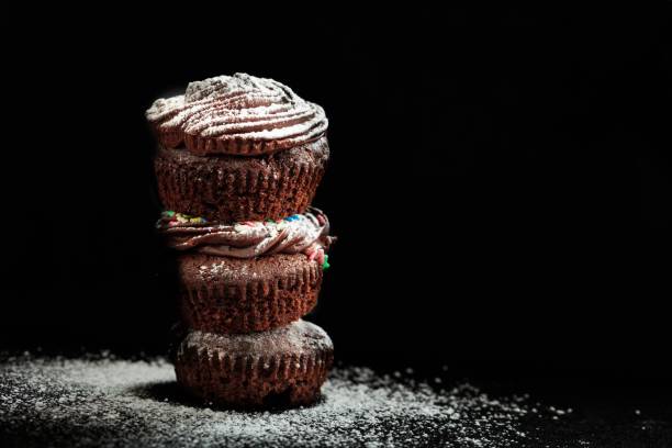 istock A pile of cup cakes on a black background 1025998024