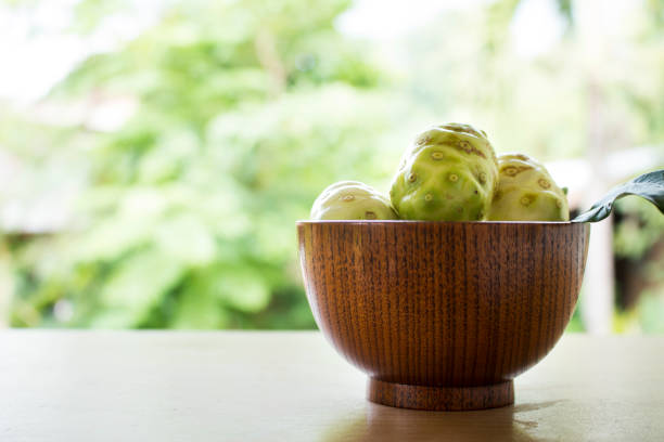 Noni or Morinda citrifolia, great morinda, Indian mulberry, beach mulberry, or cheese fruit on wood table.
