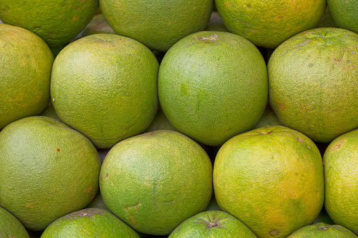 Close-up on a stack of Pomelos for sale on a market's stall.