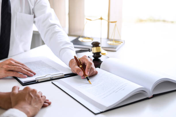 Businesspeople or lawyer having team meeting discussing agreement contract documents, judge gavel with Justice lawyers at law firm in background, Legal law, advice and justice concept stock photo