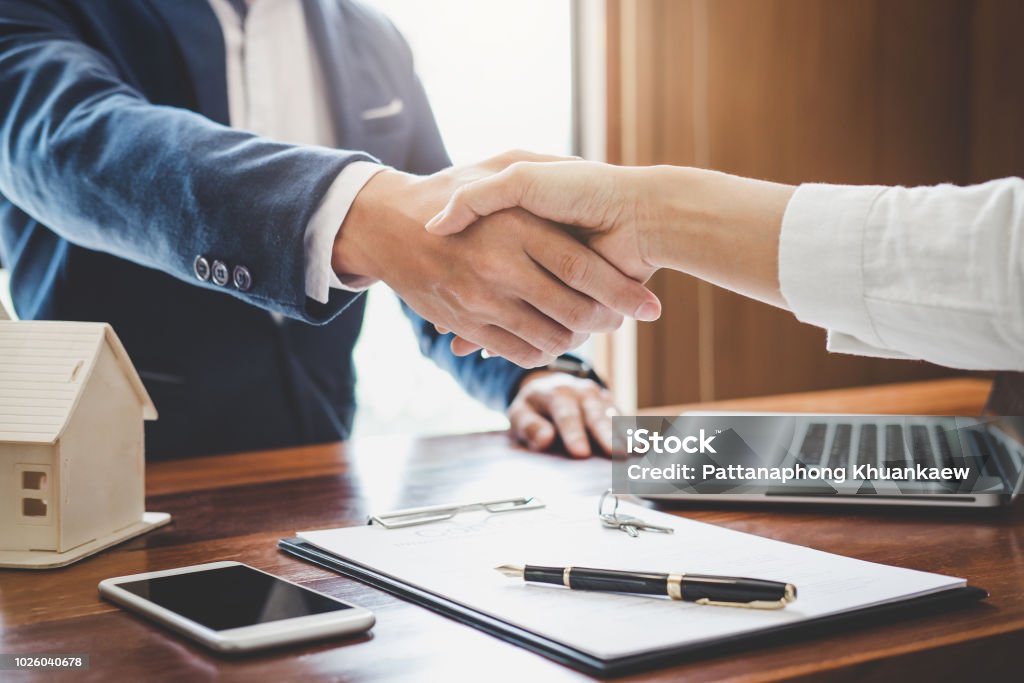 Real estate agent and customers shaking hands together celebrating finished contract after about home insurance and investment loan, handshake and successful deal Real estate agent and customers shaking hands together celebrating finished contract after about home insurance and investment loan, handshake and successful deal. Financial Loan Stock Photo