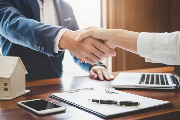 Photo of Real estate agent and customers shaking hands together celebrating finished contract after about home insurance and investment loan, handshake and successful deal