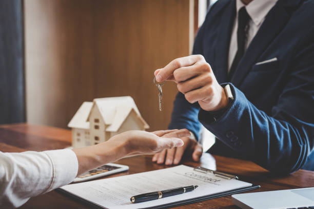 agente immobiliare responsabile commerciale che detiene le chiavi di deposito al cliente dopo la firma del contratto di locazione di affitto contratto di acquisto di vendita, relativo all'offerta di mutuo ipotecario e all'assicurazione casa - casa in affitto foto e immagini stock