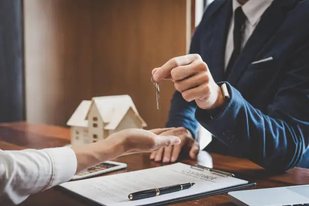 Photo of Real estate agent Sales manager holding filing keys to customer after signing rental lease contract of sale purchase agreement, concerning mortgage loan offer for and house insurance