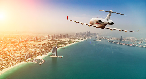 Avión jet privado volando por encima de la ciudad de Dubai en hermosa luz del atardecer. photo