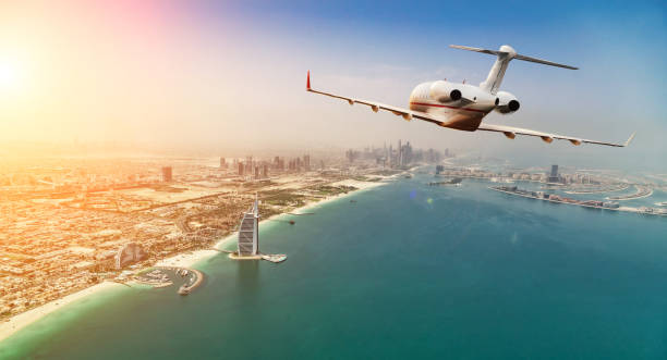 Private jet plane flying above Dubai city in beautiful sunset light. Private jet plane flying above Dubai city in beautiful sunset light. Modern and fastest mode of transportation, business life. military private stock pictures, royalty-free photos & images
