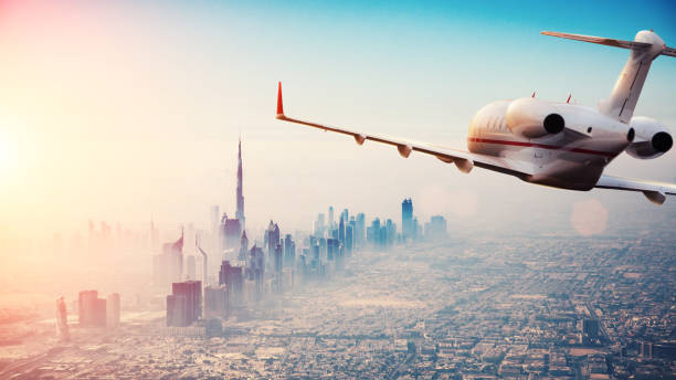 Private jet plane flying above Dubai city in beautiful sunset light.