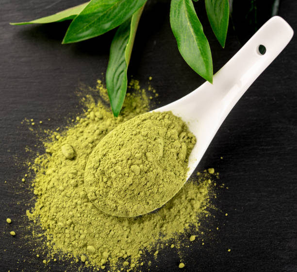 istock Matcha powder in White ceramic spoon and tea leaves on black background 1026070712