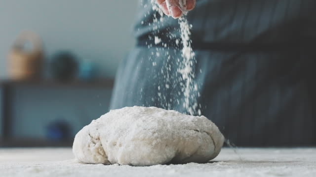 Woman sprinkling flour over dough