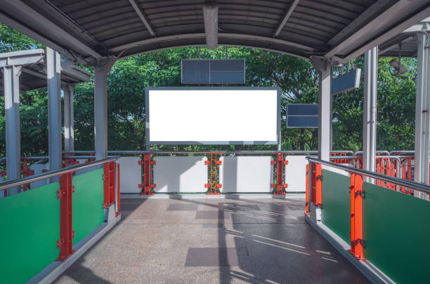 istock blank billboard white LED wide screen on concrete wall located in the walk way sky train terminal with empty copy space for display a design advertisement text template to promotion new brand. 1026078040
