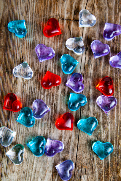 istock Multicolored glass hearts on an old wooden background. 1026089824