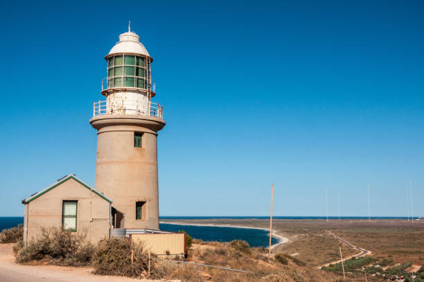 Vlaming Head Lighthouse North West Cape, Australia. Exmouth, Western Australia - November 27, 2009: Vlaming Head Lighthouse overlooking Indian Ocean against deep blue sky. Antennas of naval base on horizon. exmouth western australia photos stock pictures, royalty-free photos & images