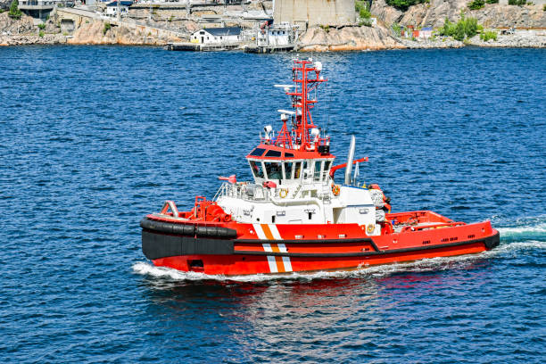 красный буксир отправляется на миссию из гавани в море - fire boat стоковые фото и изображения