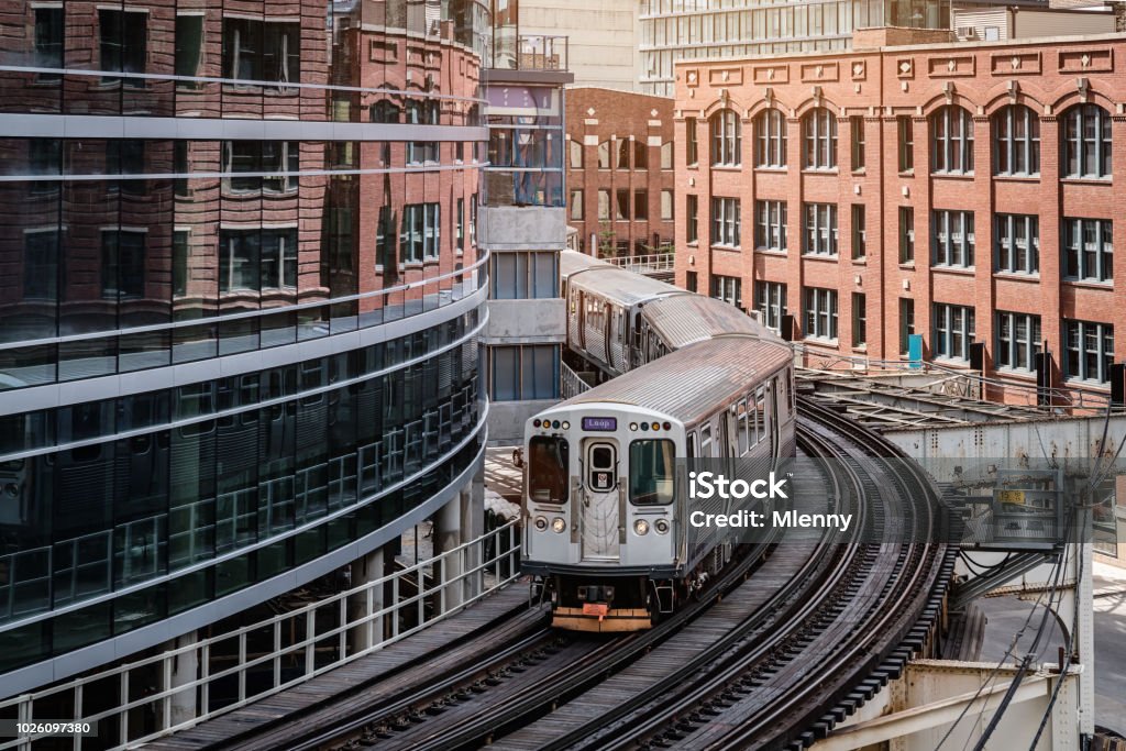 Chicago CTA Train between City Buildings Chicago typical silver colored commuter train moving on elevated tracks to railroad station in between urban city buildings of Chicago, Illinois, USA. Chicago - Illinois Stock Photo