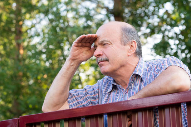 Mature caucasian man carefully watching over the fence. stock photo