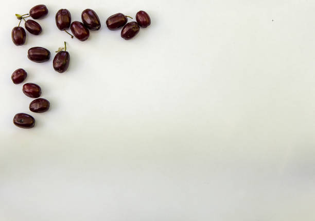 Fresh ripe cornelian cherry dogwood berry white paper with copy space. stock photo