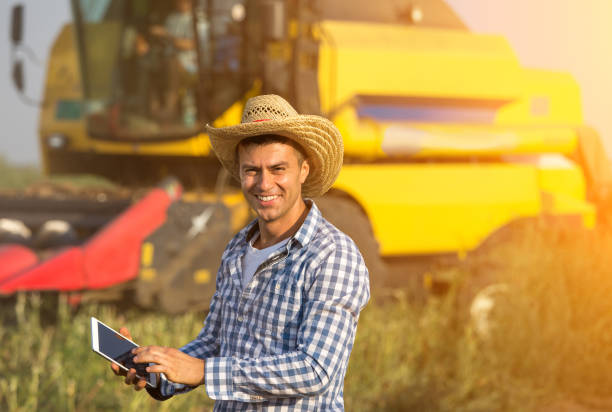 Farmer with tablet in front of combine harvester
