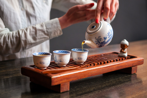 Cropped shot of woman pouring tea in traditional chinese teaware.