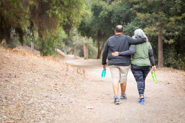 Senior Mexican Couple Enjoying a Walk in Nature A senior mexican couple in casual athletic attire walking in a nature park fat mexican man pictures stock pictures, royalty-free photos & images