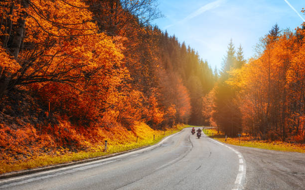 Bikers on mountainous highway, biker on the road in sunset light in autumn riding on curve road pass across Alpine mountains, extreme lifestyle, freedom concept. Austria, Alps ciclistas en carretera montañosa, ciclista en la carretera en la luz del atardecer en otoño del montar a caballo en el camino de la curva pasan a través de las montañas alpinas, estilo de vida extrema, concepto de libertad. austria, alpes