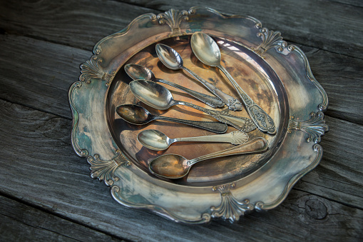 Ancient little spoons on a vintage silver platter, tray. Vintage cutlery, kitchen utensils as concept,