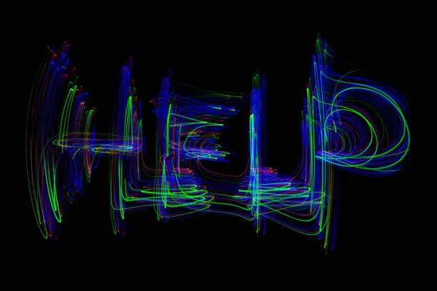 The word ‘HELP’ painted in the air in motion trails, captured on a long exposure. This text light painting on a black background consists of vibrant neon colours which are abstract, modern, stylish and unique.