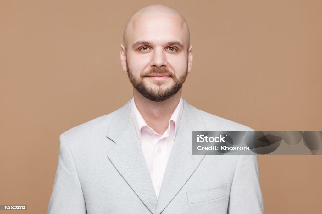 Portrait de heureux âge moyen beau chauve barbu homme d’affaires classique costume gris clair permanent et regardant la caméra avec le sourire. - Photo de Complètement chauve libre de droits