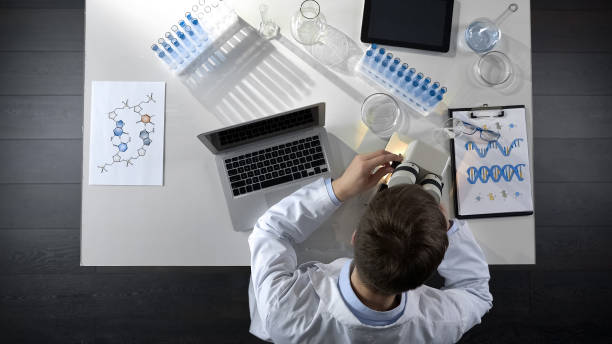 istock Male analyst doing observations of sample under microscope, lab research topview 1026202640