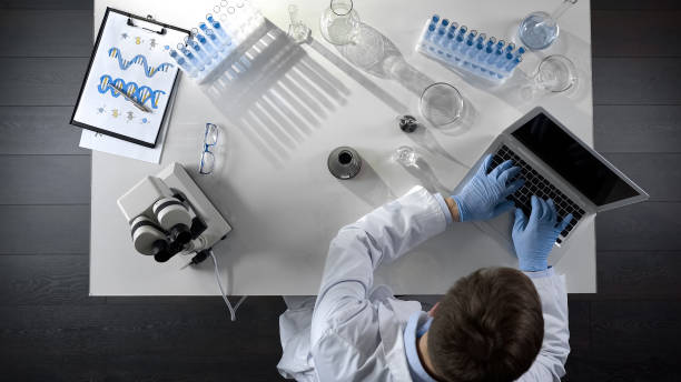 istock Chemist writing down results of chemical experiments on computer, top view 1026202722