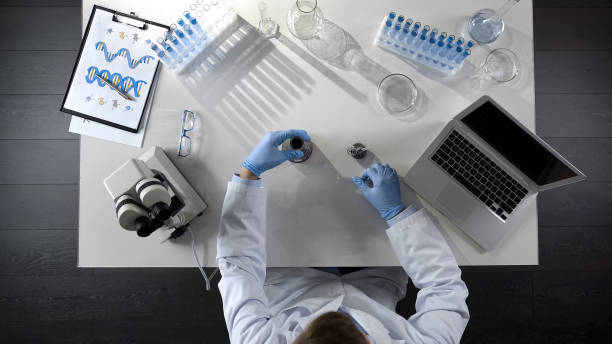 istock Lab assistant checking oil product in flask, making chemical mixture, top view 1026202726