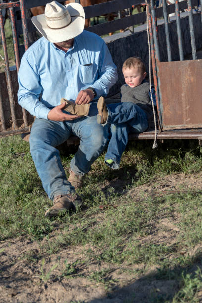 istock Cowboy father helps young son with his boots 1026220912