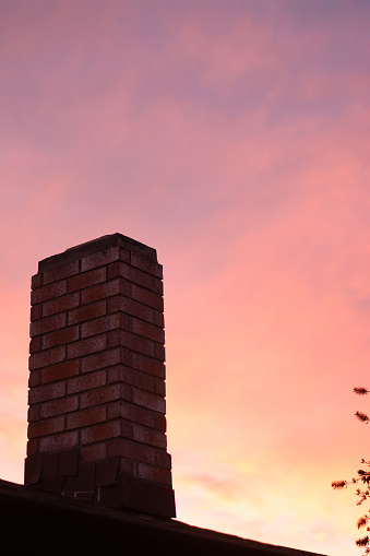Close up brick chimney of house on background of blue pink sky during sunset