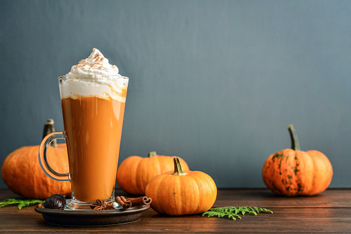 Pumpkin spice latte with whipped cream on wooden background