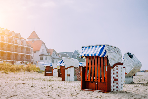 Blue striped roofed chairs on sandy beach near resort Travemunde in sun light in low season. Germany