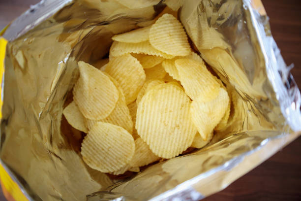 istock Potato chips in open snack bag close up on table floor 1026273102