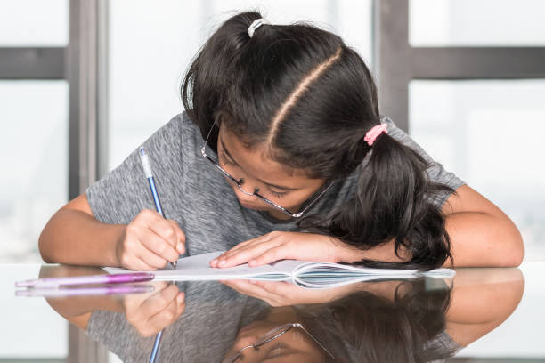 istock Educational back to school concept with elementary school Asian girl kid student studying doing homework writing on desk 1026273128
