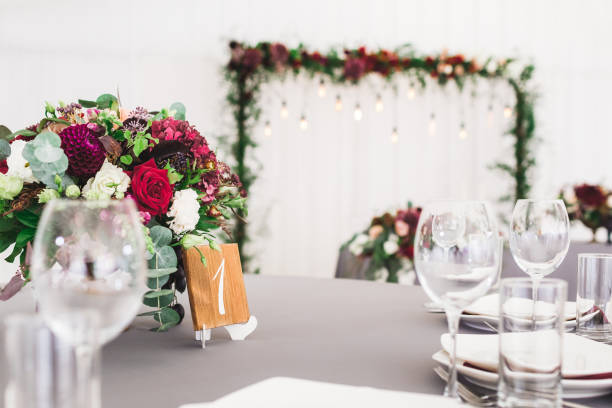 istock Wedding table, decorated with red flowers bouquets, candles, grey tablecloth, and white plates 1026273322