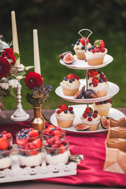 istock Fresh tasty cupcakes with berries on wedding reception table, decorated in red colour with flowers 1026273436