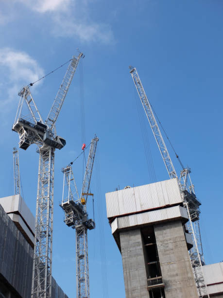 istock tall construction cranes working in a large building site surrounding large concrete structures 1026279608
