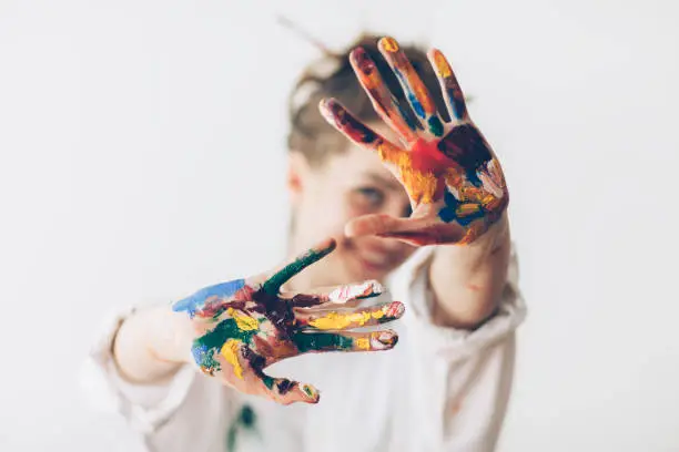 Photo of Happy woman hiding the face with her painted hands