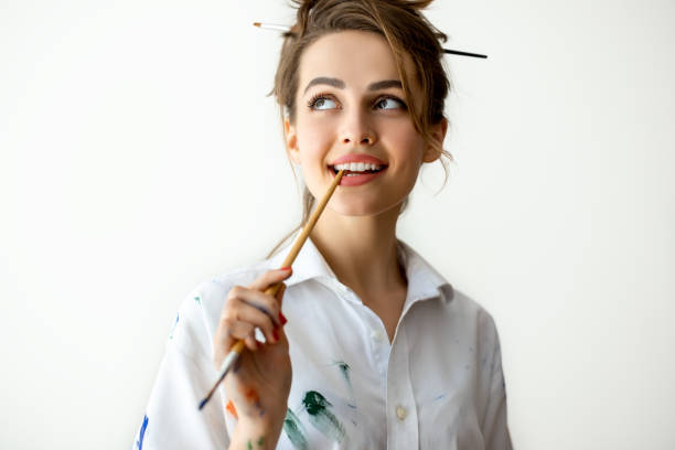 istock Beautiful young woman biting brush in thoughts 1026279744