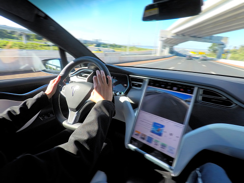 AUCKLAND - AUG 12 2018:Person drives a Tesla plug-in electric car Model X, a luxury, crossover utility vehicle (CUV) , on a motorway. in 2016 seventh among the world's best-selling plug-in cars.